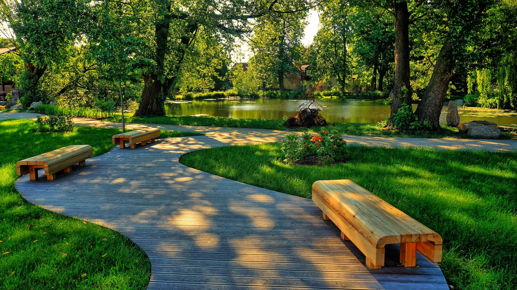 A garden with shaded paths, a pond and benches